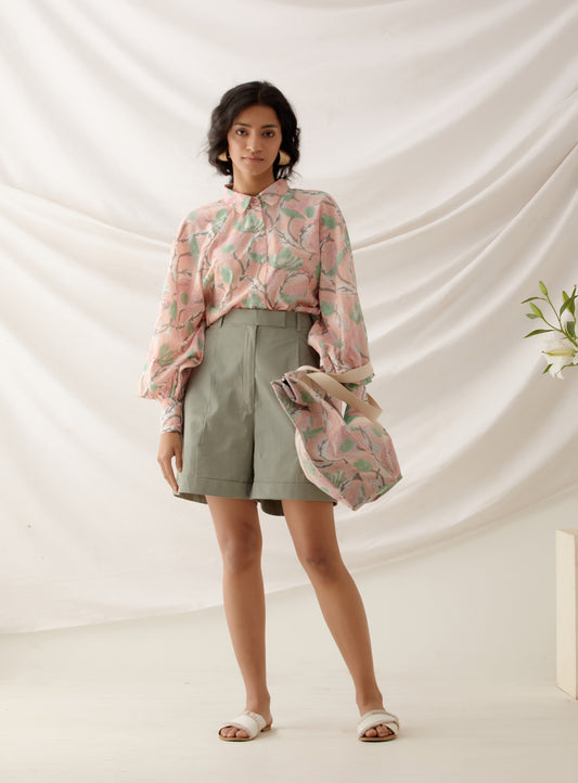 woman wearing  handcrafted floral block printed peach  co ord set with khaki shorts .