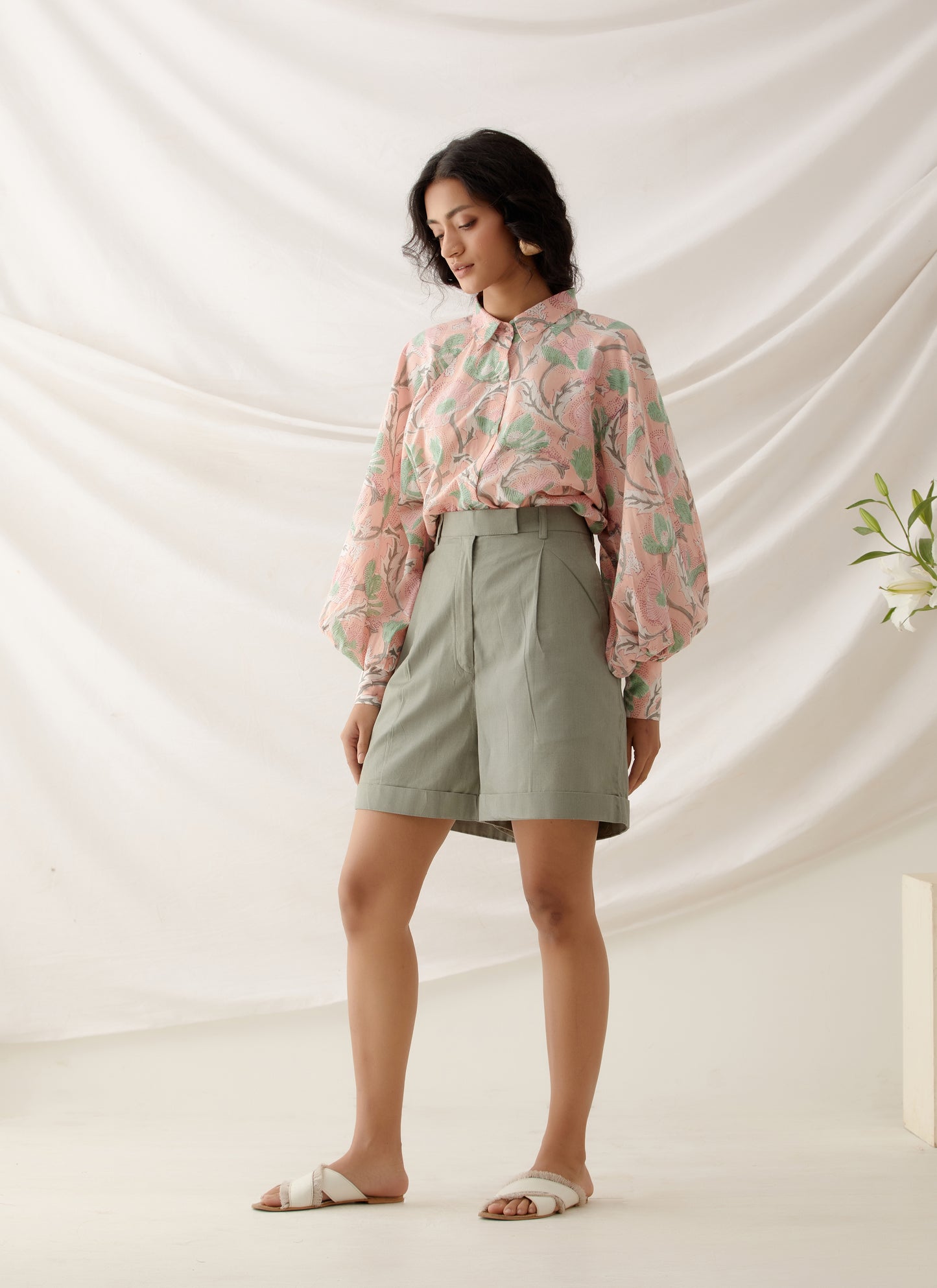 woman wearing handcrafted floral block printed peach co ord set with khaki shorts .