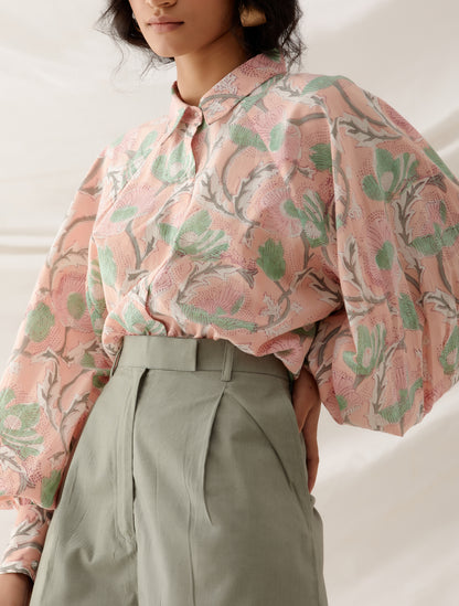 woman wearing handcrafted floral block printed peach co ord set with khaki shorts .
